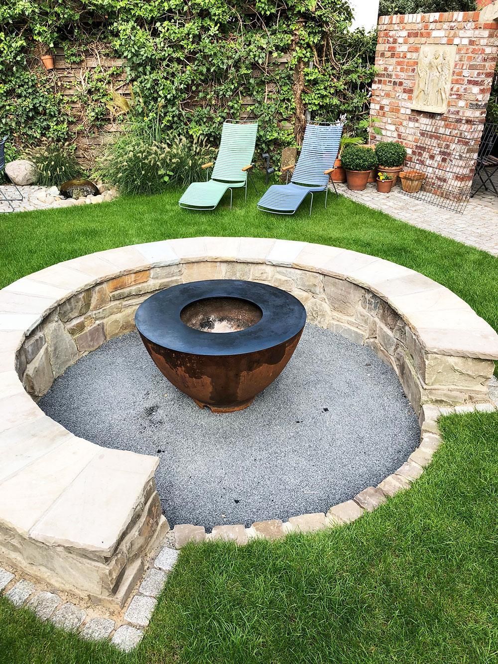 Eine Feuerstelle inmitten eines üppigen grünen Rasens.