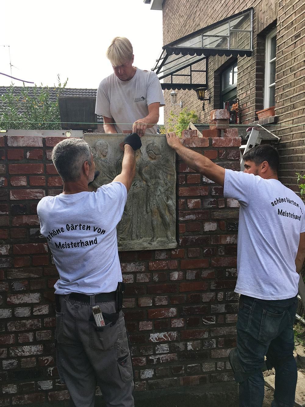 Eine Gruppe Männer arbeitet an einer Ziegelmauer.