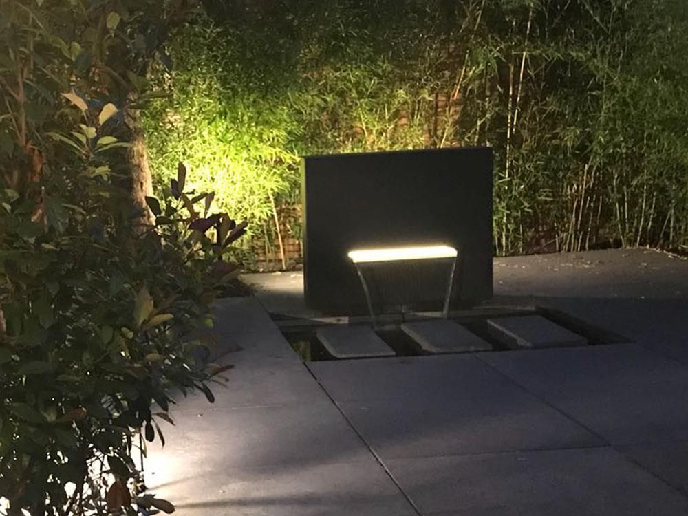 In einem Garten ist nachts ein Springbrunnen beleuchtet