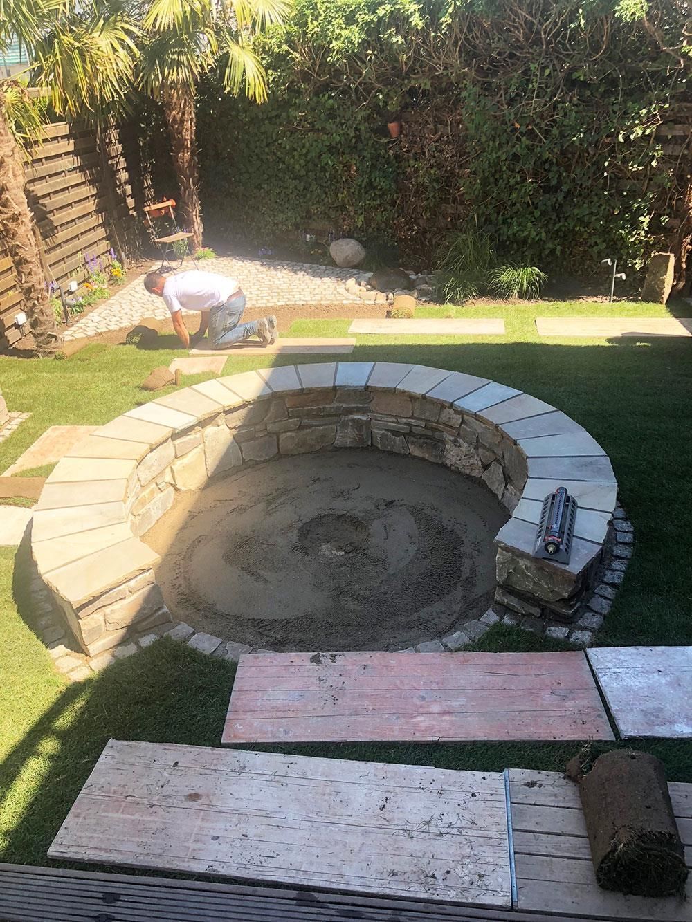 Ein Mann arbeitet an einer Feuerstelle in einem Hinterhof.