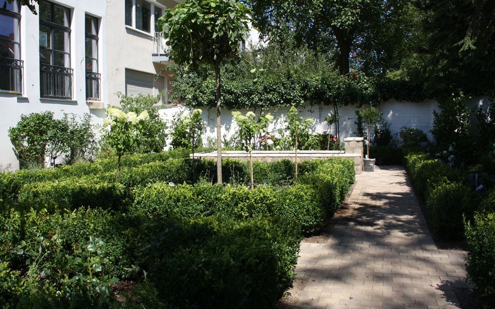 Ein Garten mit Bäumen und Sträuchern vor einem Gebäude