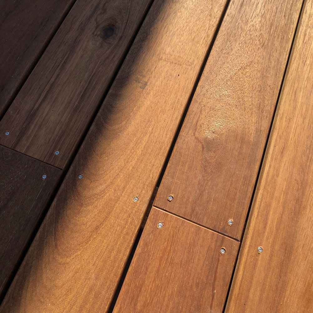 Eine Nahaufnahme von einem Holzdeck mit Schrauben darauf
