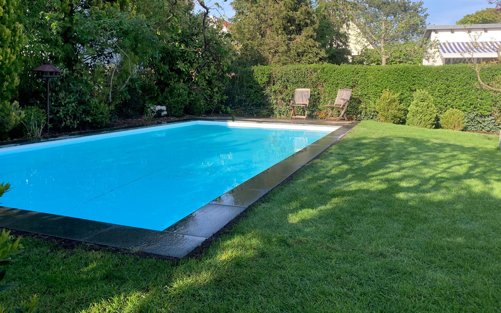 Inmitten eines üppig grünen Hofes befindet sich ein großer Swimmingpool.