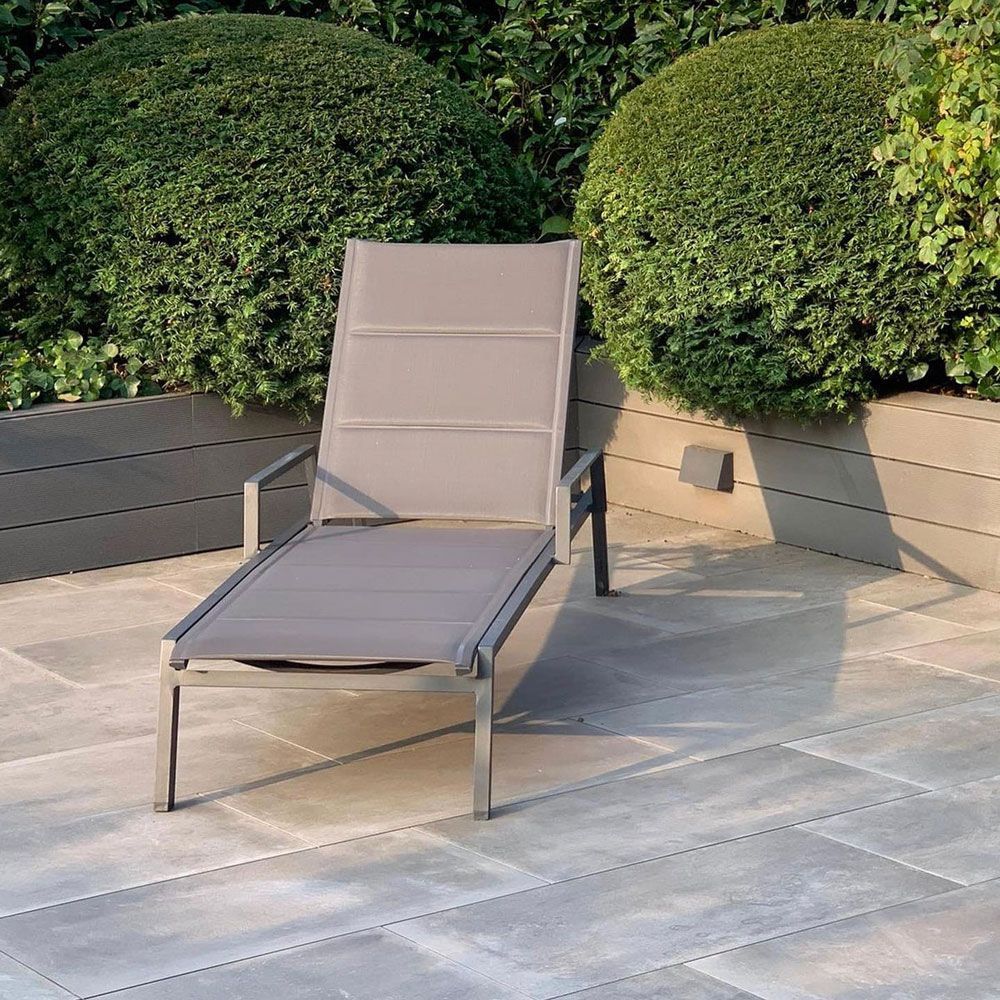 Ein grauer Loungesessel steht auf einer gefliesten Terrasse