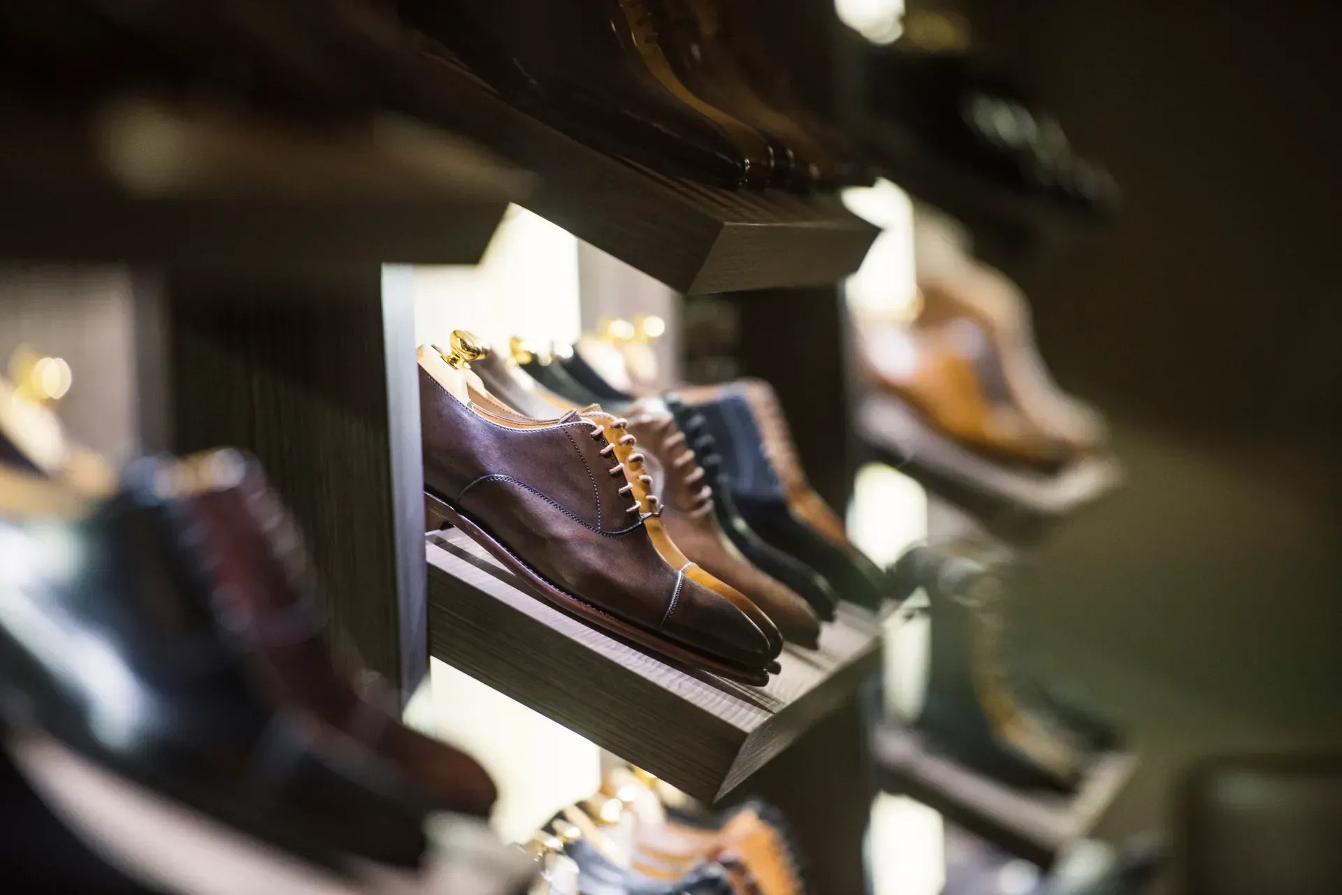 Una fila de zapatos de hombre se exhiben en un estante de una tienda.