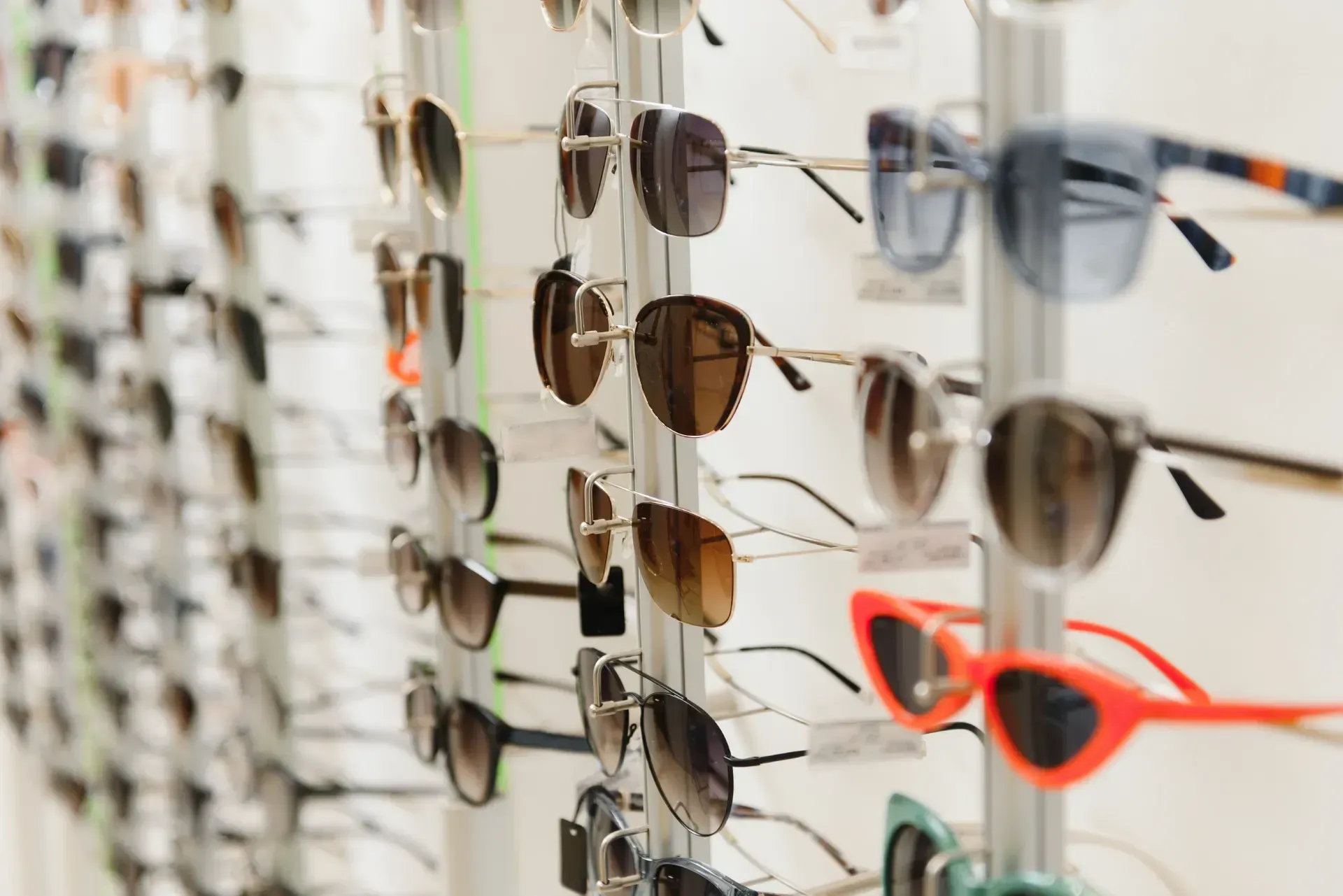 Una fila de gafas de sol colgadas en un estante en una tienda de óptica.