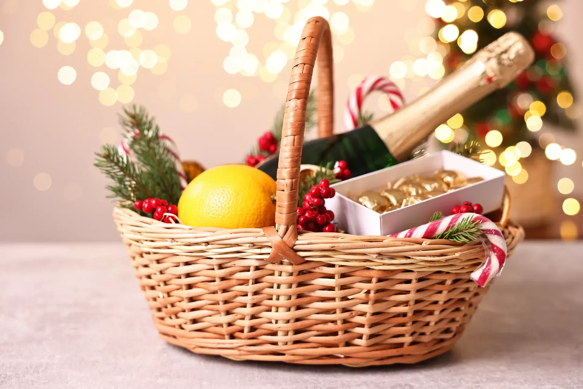 Una cesta de mimbre llena de adornos navideños y una botella de champán.