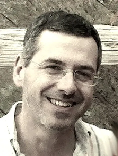 Un hombre que lleva gafas sonríe en una foto en blanco y negro.