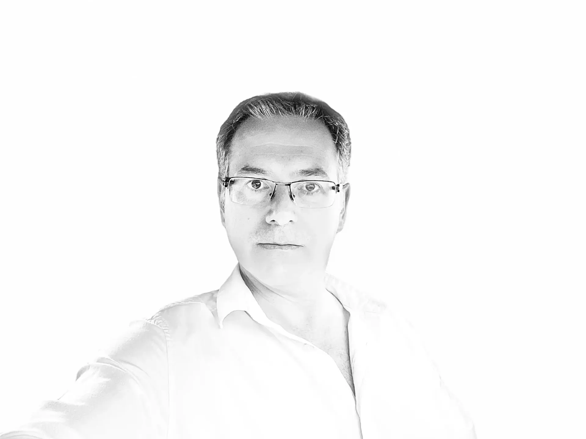Un hombre que lleva gafas y una camisa blanca se está tomando un selfie.