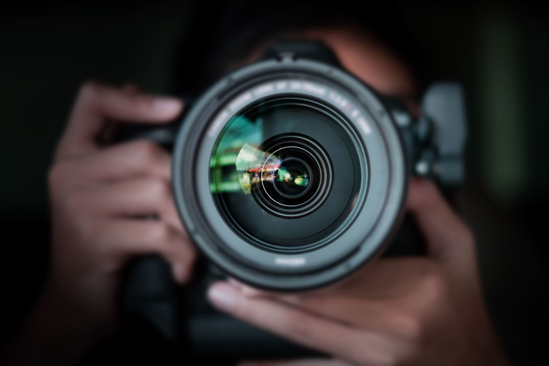 Gros plan sur l'objectif d'un appareil photo tenu par un homme