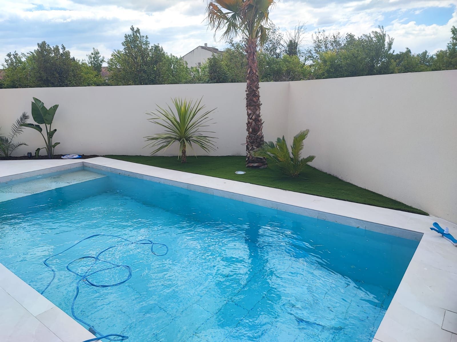 Piscine avec un bout de terrain avec du gazon synthétique coupé en triangle