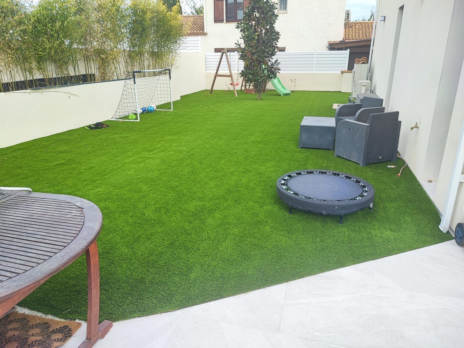 Gazon synthétique avec un salon de jardin et une balançoire dessus