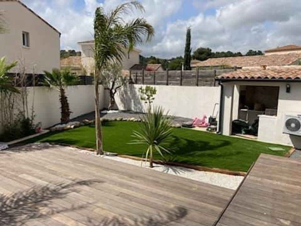 Terrasse en bois avec gazon synthétique posé dans un endroit délimité par des bordures