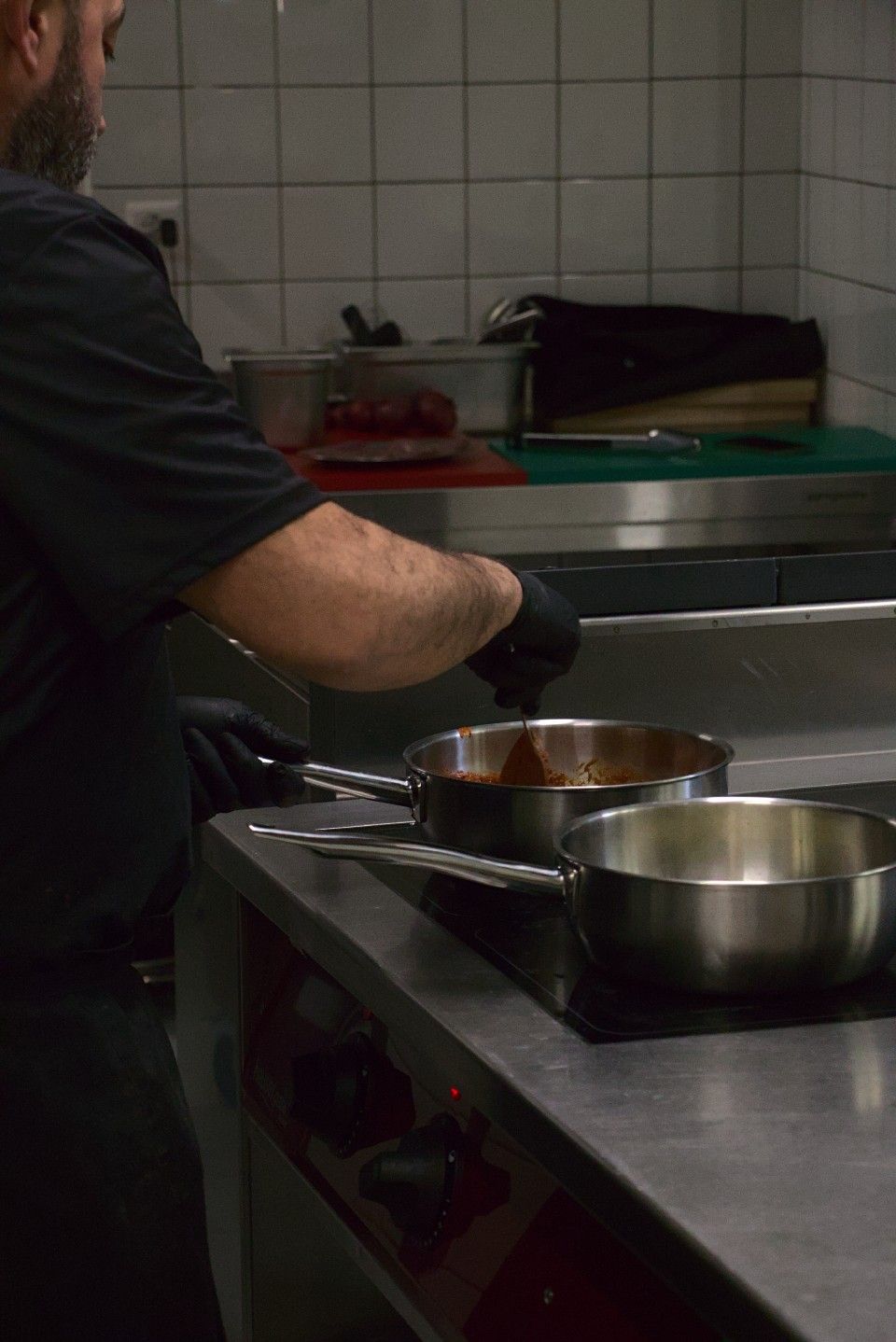 Ein Koch rührt eine Sosse in einer Edelstahlpfanne auf dem Herd.