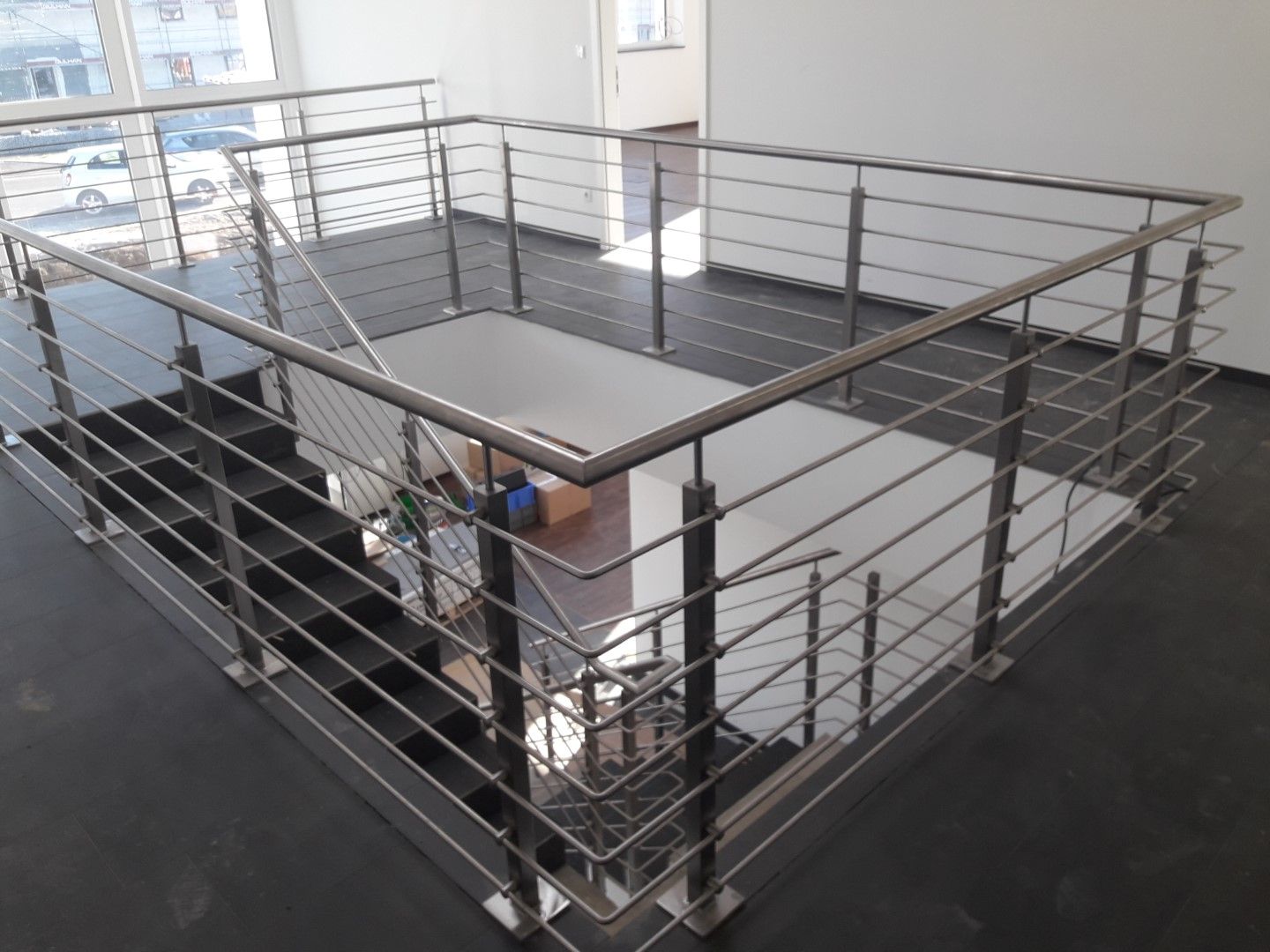 Ein Edelstahlgeländer umgibt eine Treppe in einem modernen Gebäude.