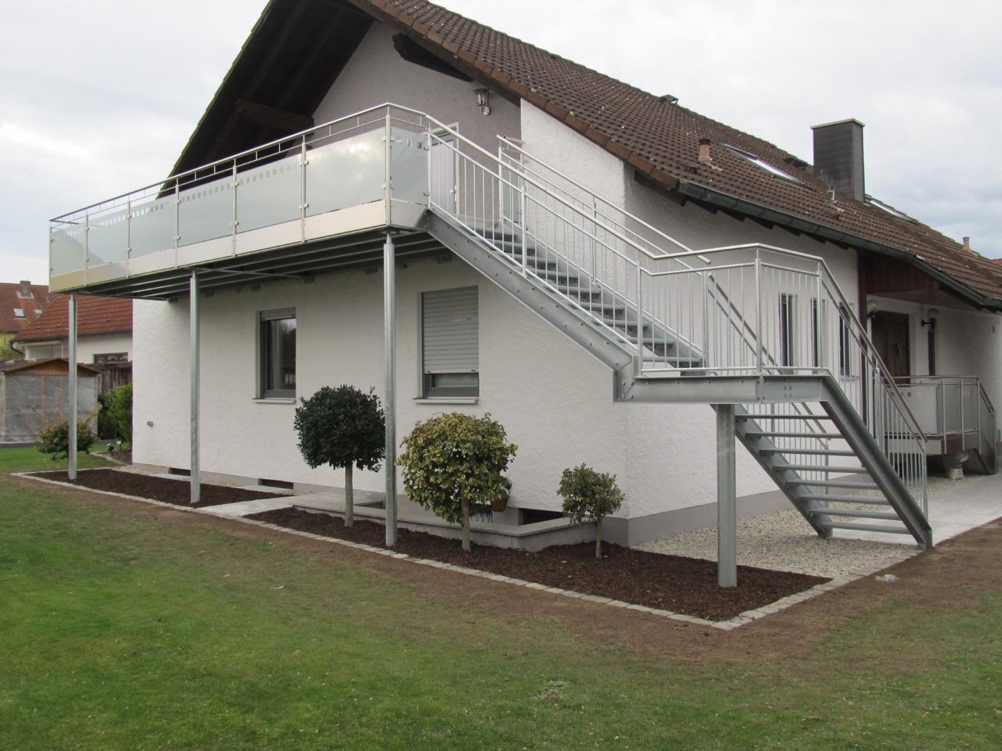 Ein zweistöckiges Haus mit einem Balkon und einer Treppe aus Metall.