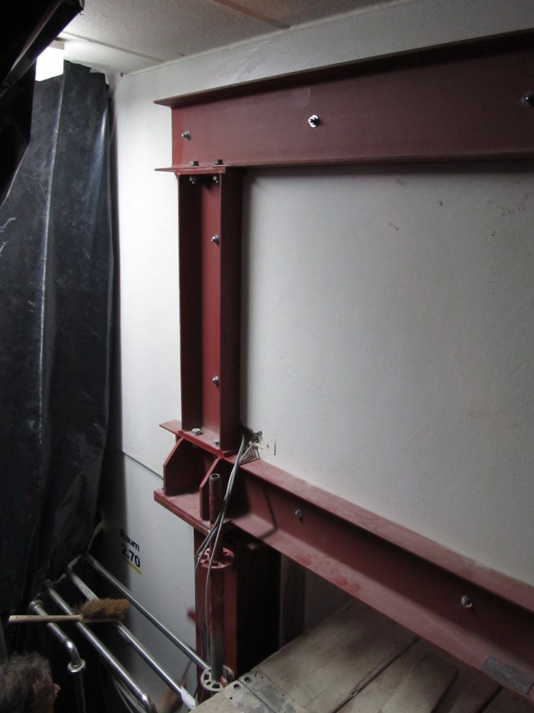 Roter Stahlträgerrahmen, an weiße Wand geschraubt, wahrscheinlich zur strukturellen Unterstützung.