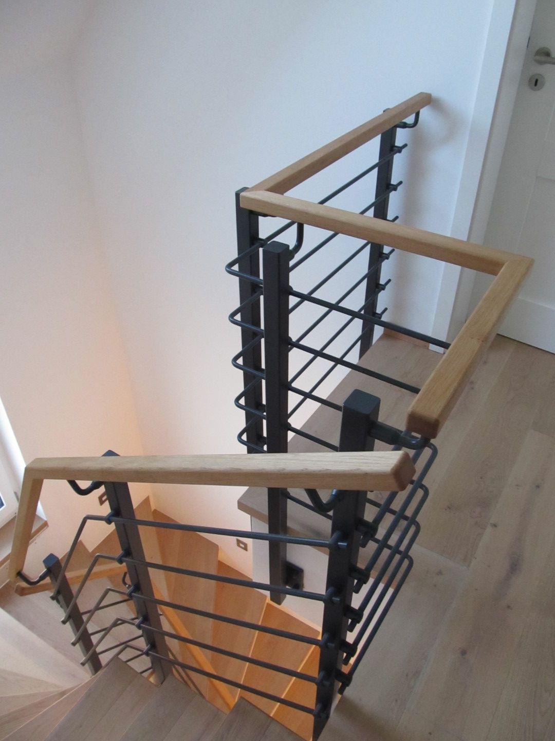 Holztreppe mit schwarzem Handlauf aus Metall und Holz.