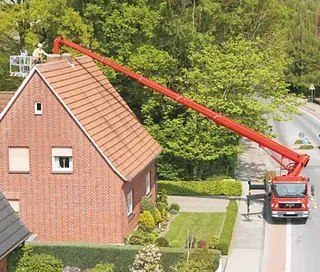 Ein roter LKW steht vor einem Backsteinhaus