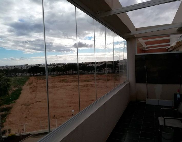 Un balcón con muchas ventanas y vista a un campo.
