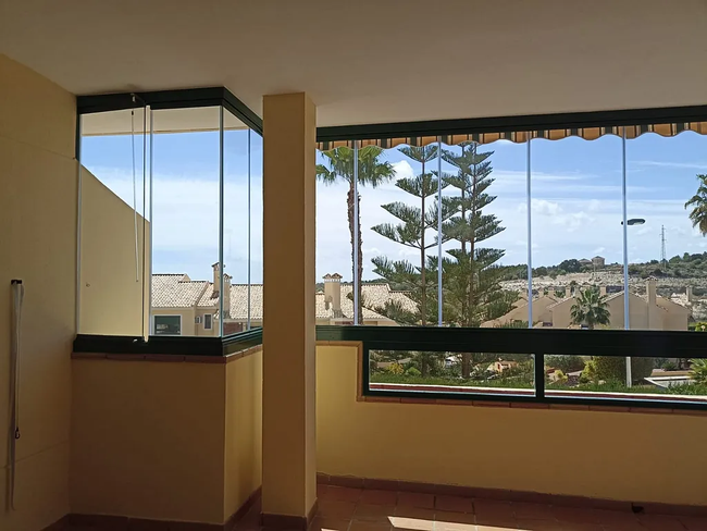 Una habitación con muchas ventanas y árboles al fondo.