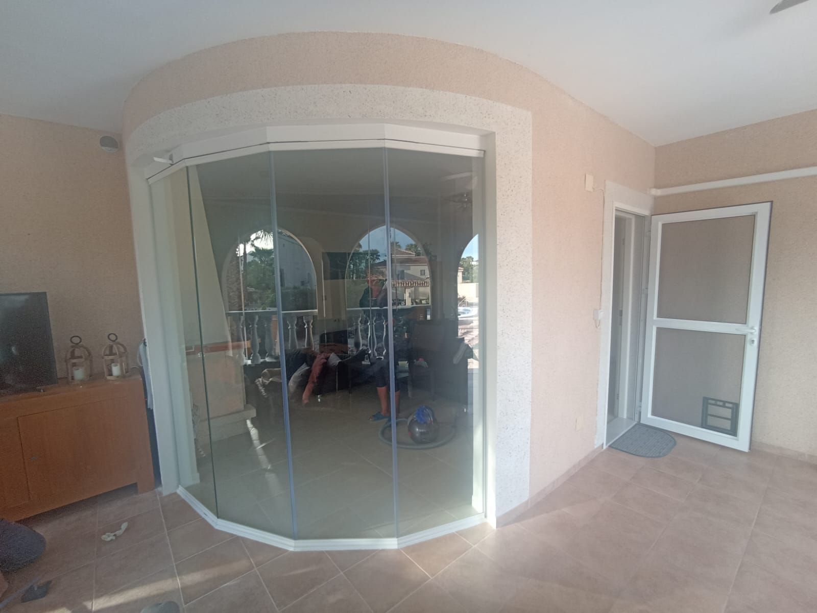 Una habitación con una puerta de vidrio curva y una puerta de vidrio corrediza.