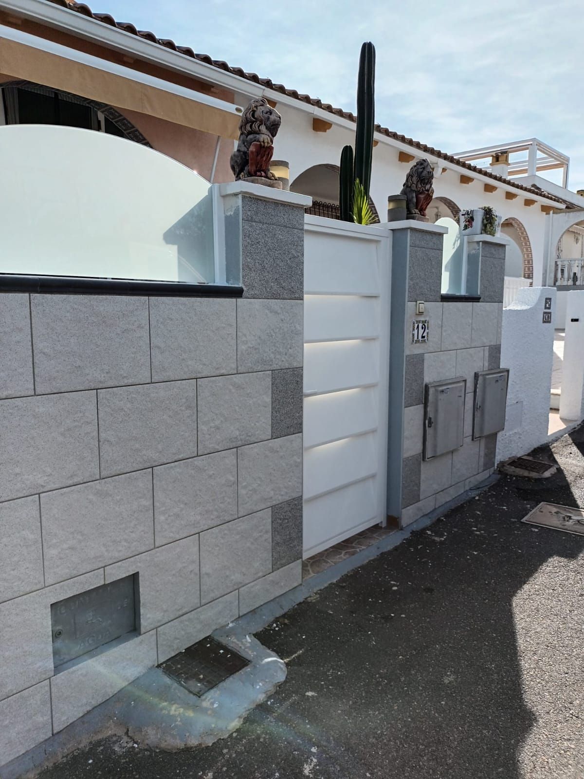 Un edificio con una valla y un cactus delante.