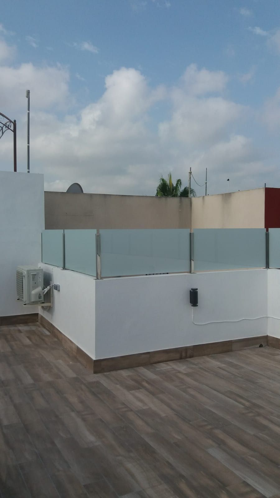 Una terraza en la azotea con una valla de cristal y un suelo de madera.