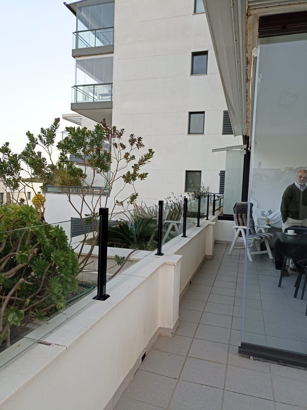 Un hombre está de pie en un balcón al lado de un edificio.