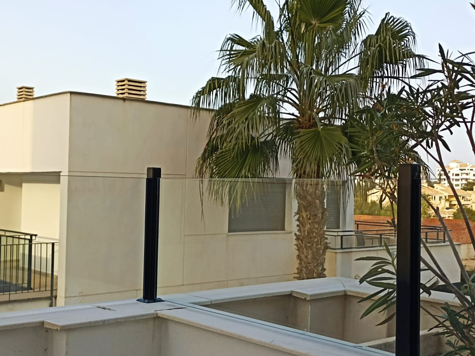 Un edificio blanco con una palmera delante.