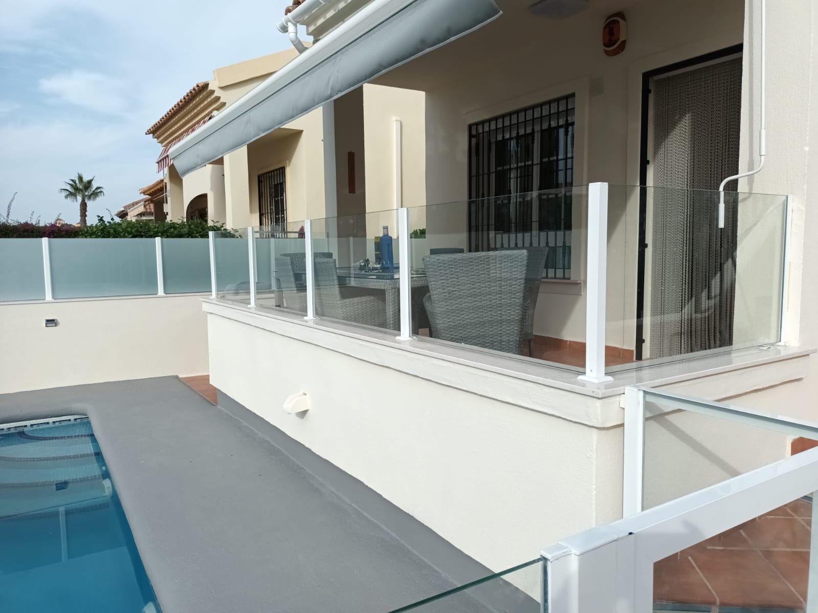 Una casa con piscina y barandilla de cristal