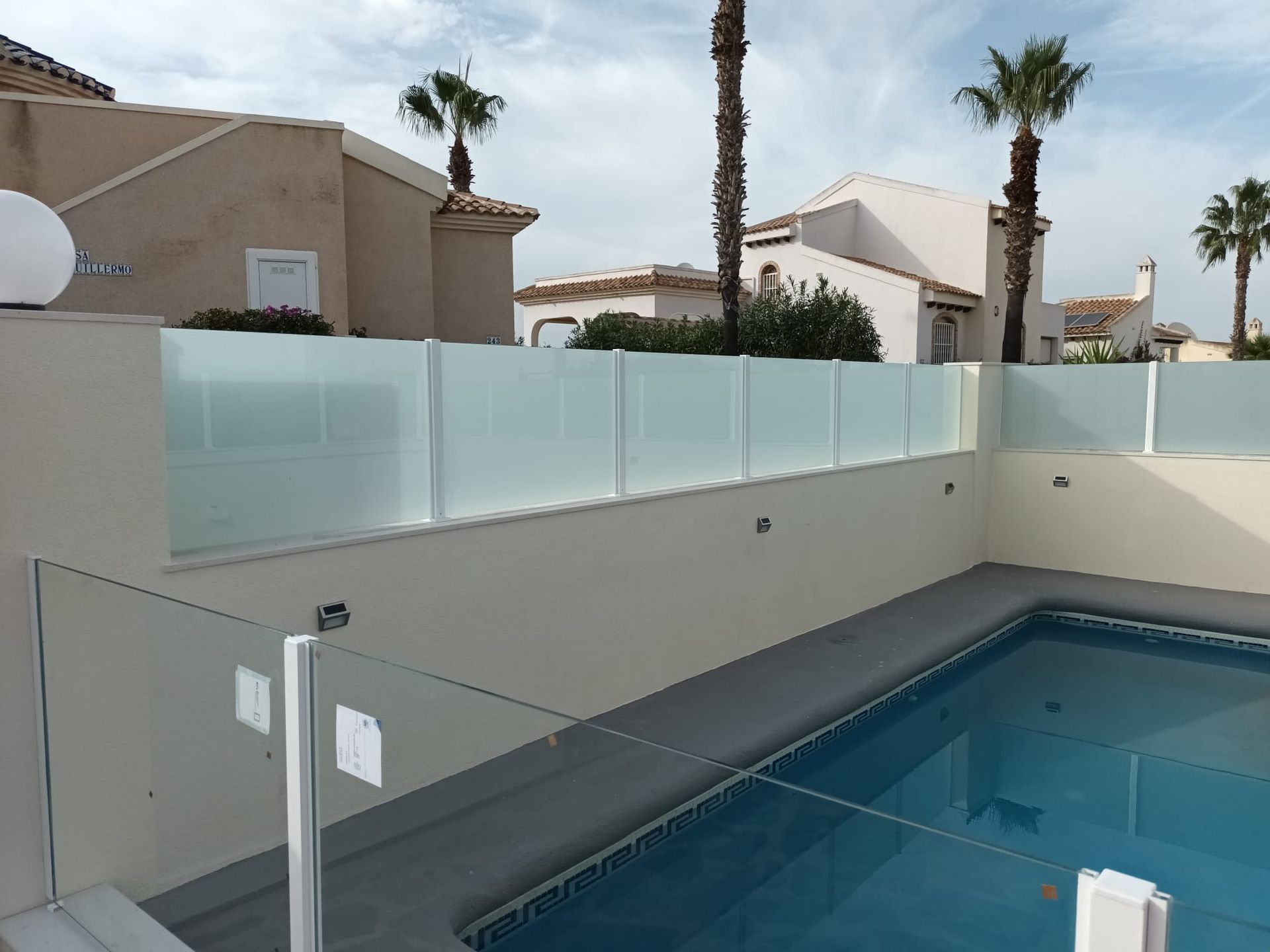 Una piscina con una valla de cristal a su alrededor.