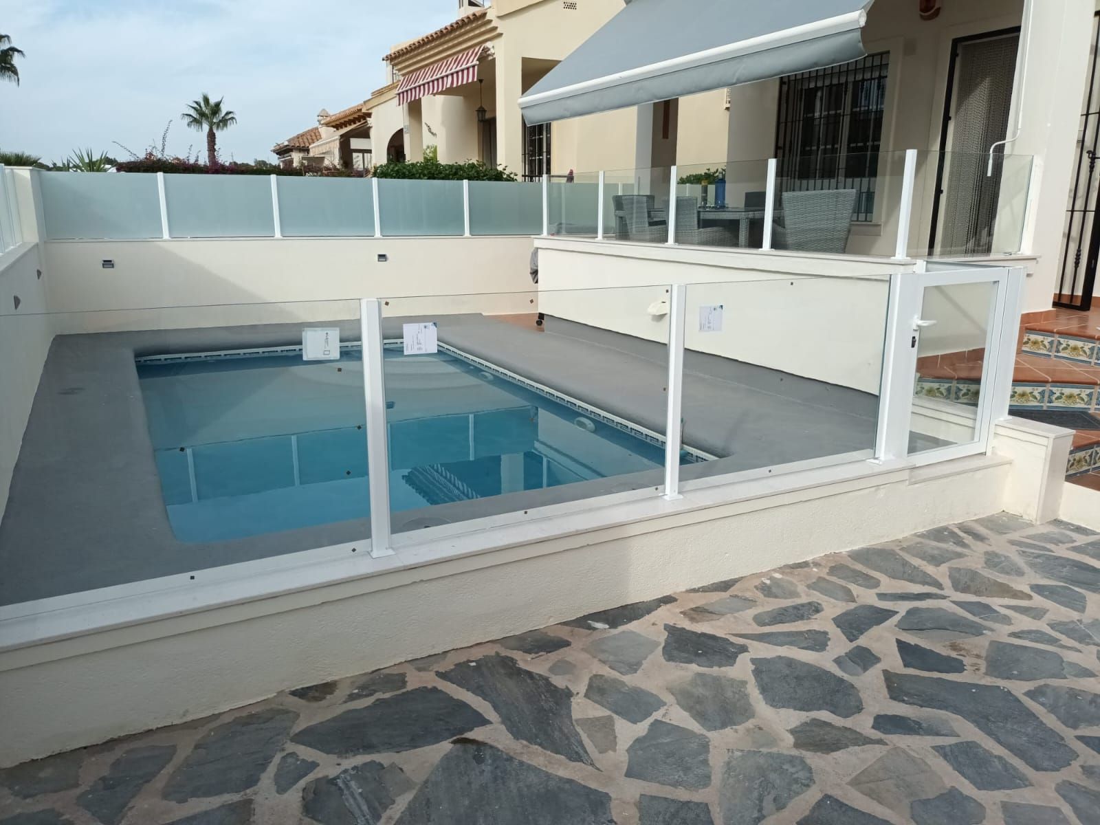 Una piscina con una valla de cristal a su alrededor.