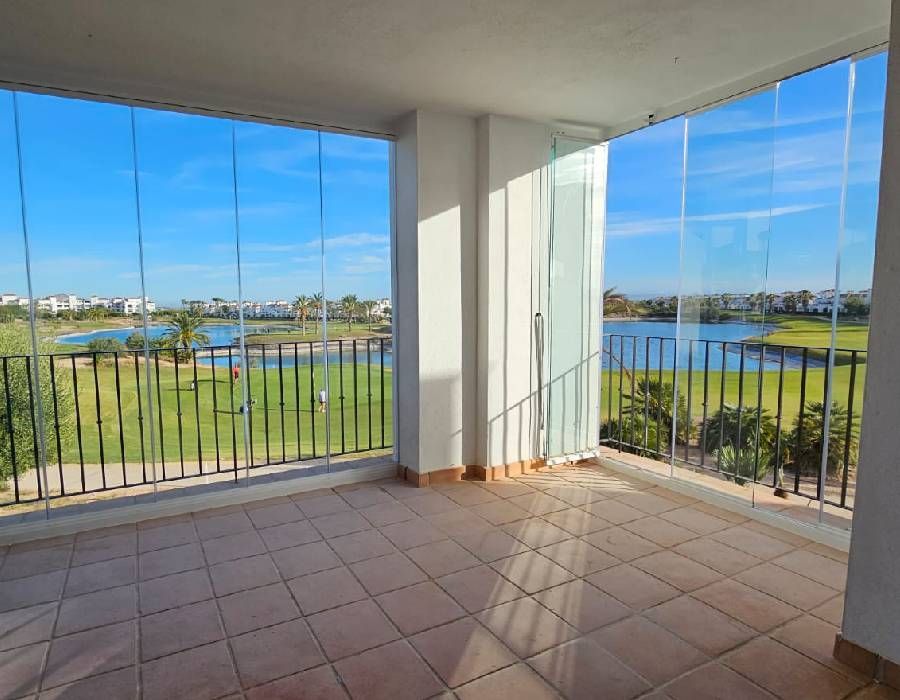 Un balcón vacío con vista a un campo de golf y un lago.