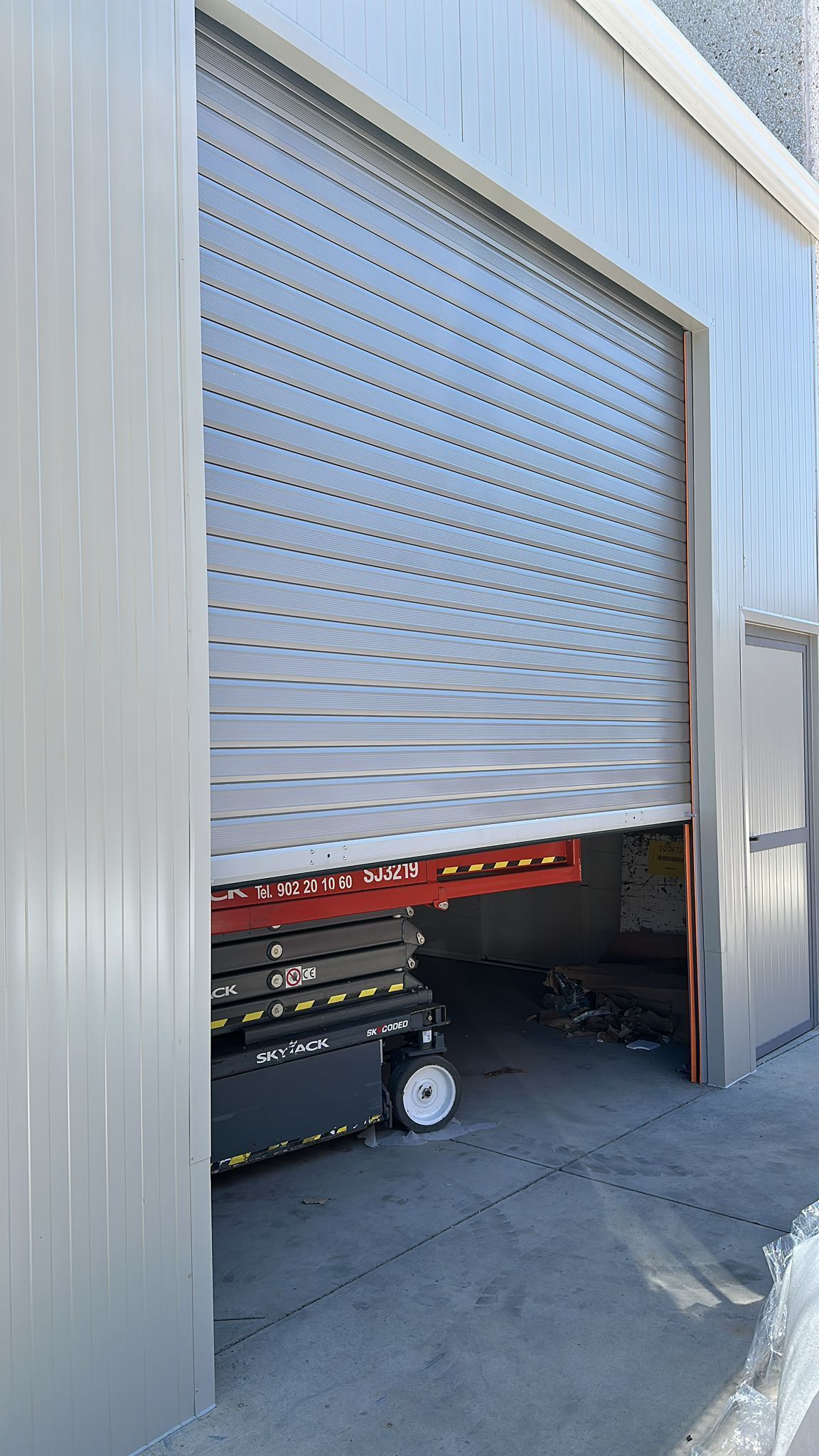 Una puerta de garaje está abierta y un elevador de tijera está estacionado en el garaje.