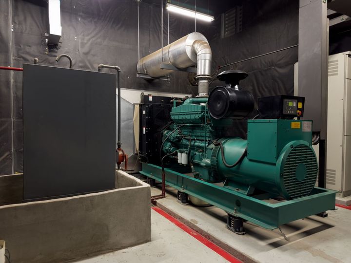 Ökostromgenerator in einem Industrieraum mit Lüftungskanälen und einer dunklen, schallgedämmten Wand.