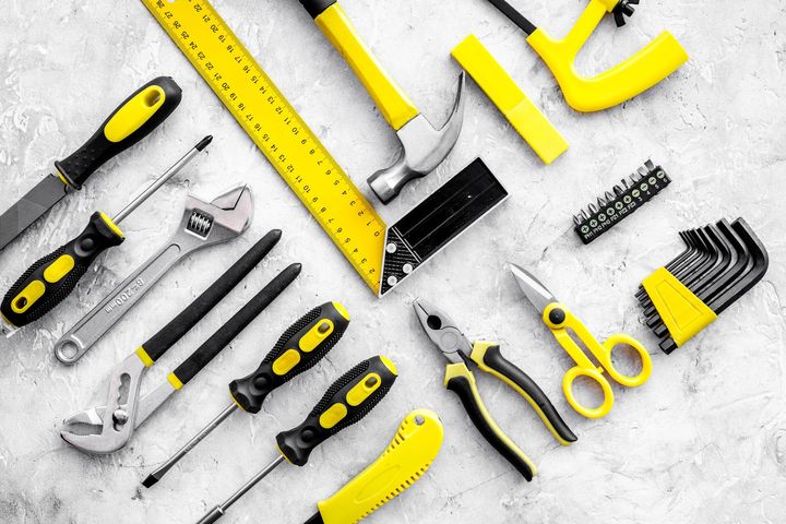 Ensemble d'outils de bricolage jaune posés sur un sol blanc