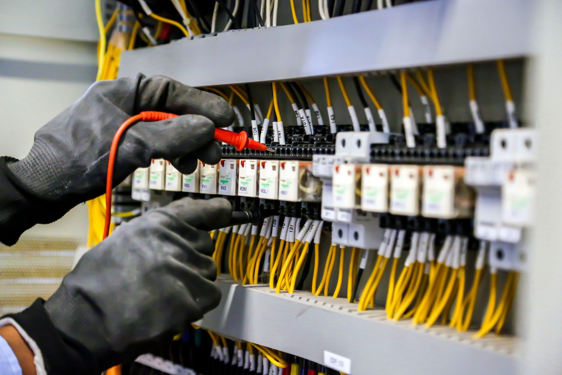 Mesure d'un tableau électrique avec des câbles jaune à l'aide d'un multimètre