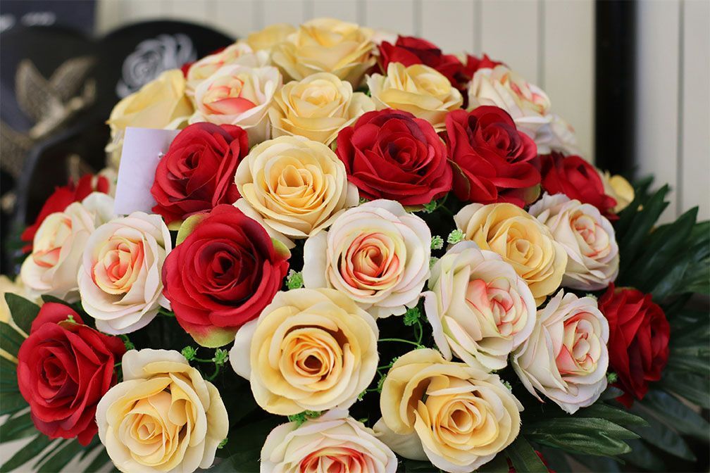Gros plan sur un bouquet de roses rouges, jaunes et crème.
