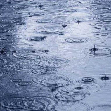Ondulations à la surface de l'eau dues à la chute de gouttes de pluie. Tons bleus et gris.