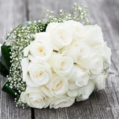 Bouquet de roses blanches et de gypsophile sur une surface en bois patinée.