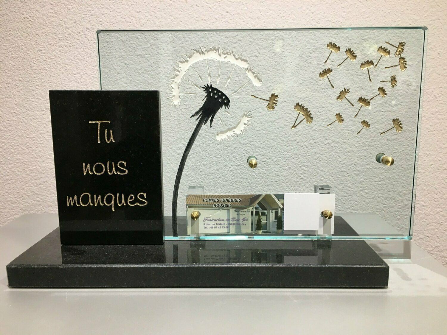 Une plaque funéraire en verre et granit avec une gravure.