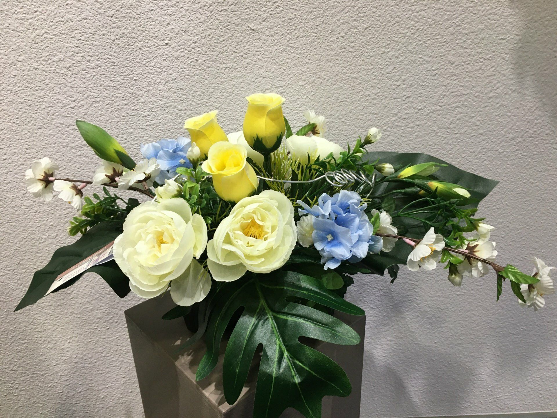 Composition de fleurs jaunes et bleues artificielles.