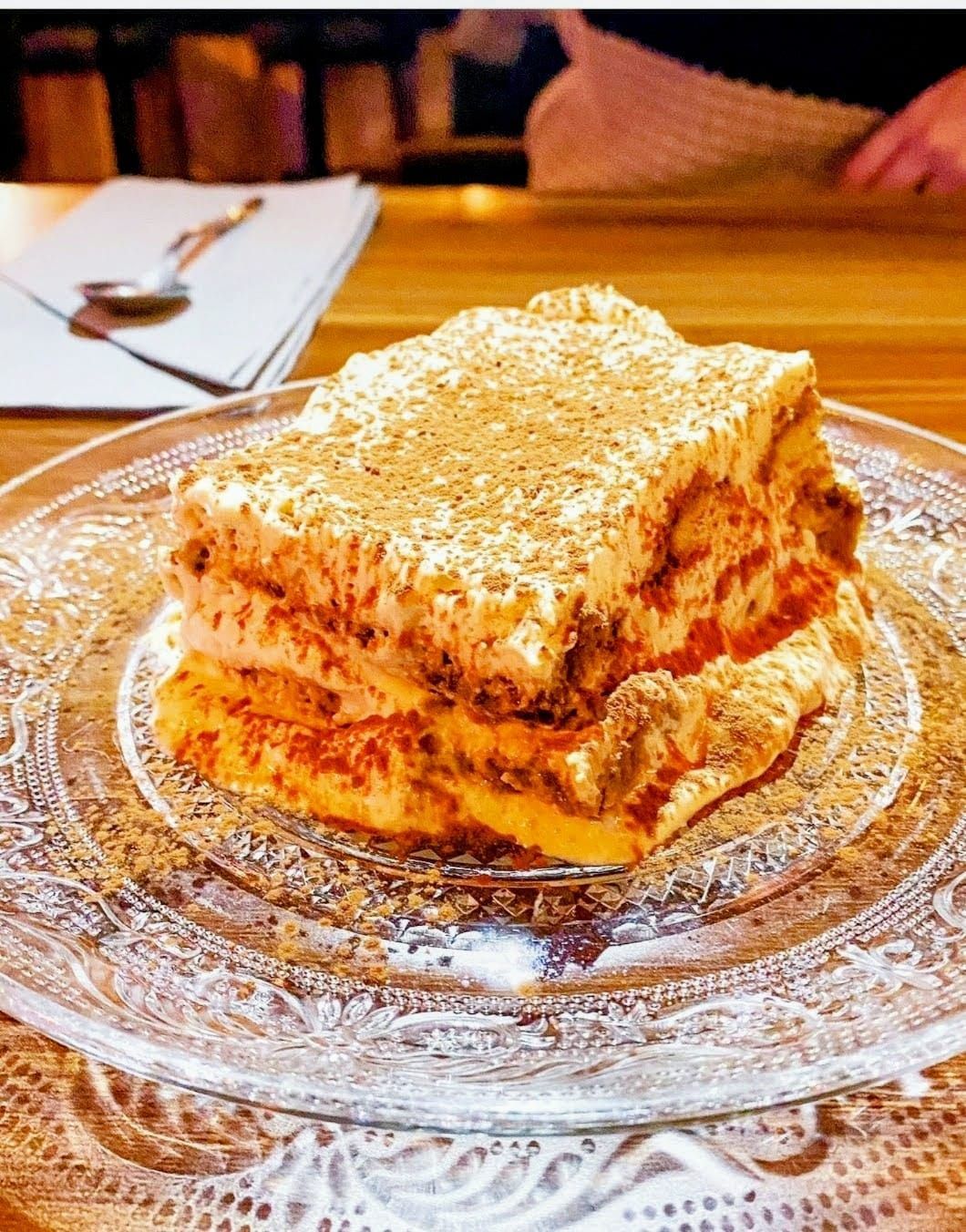 Una rebanada de lasaña está en un plato de vidrio.