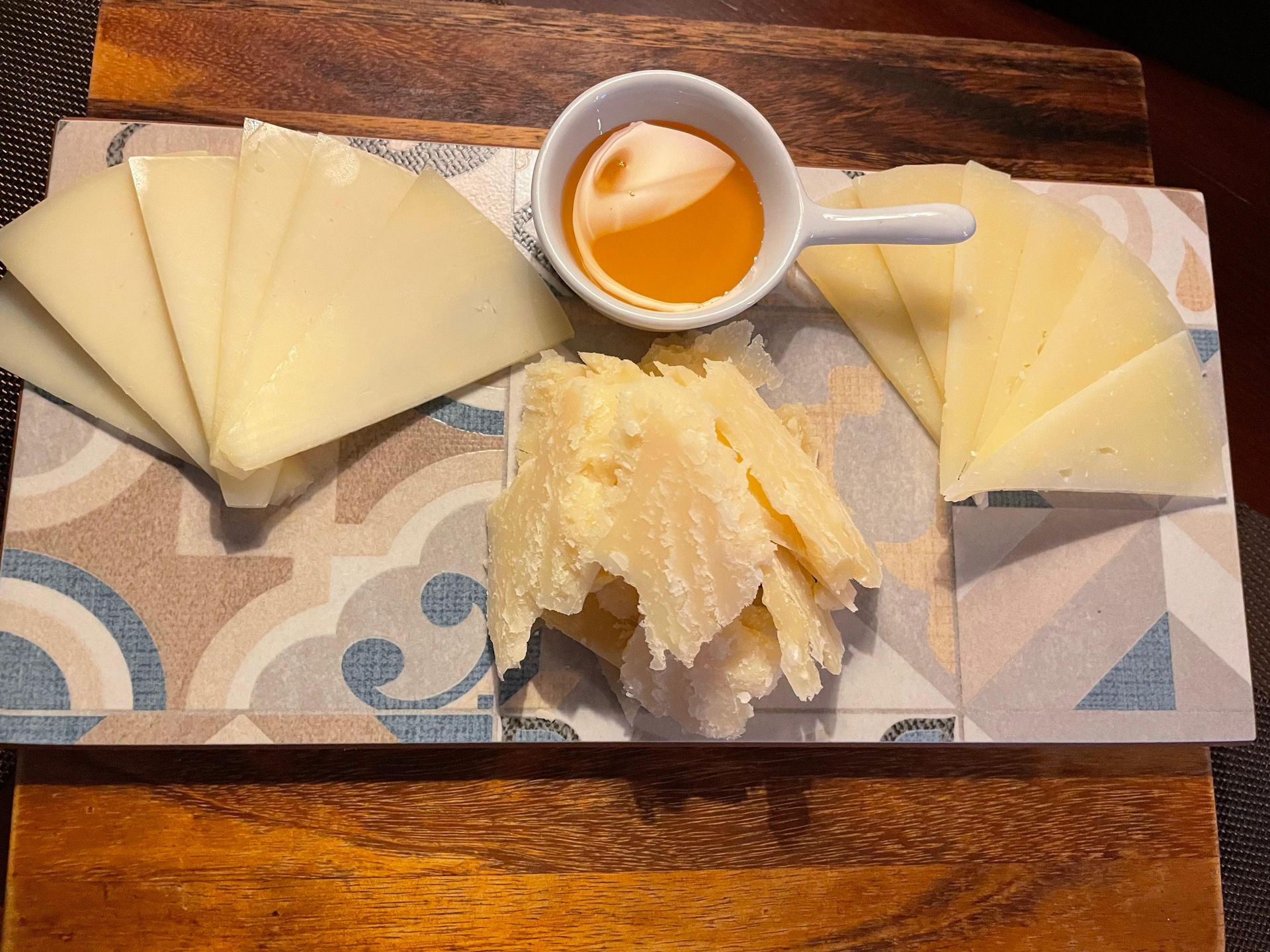 Una bandeja de queso y miel sobre una mesa de madera.