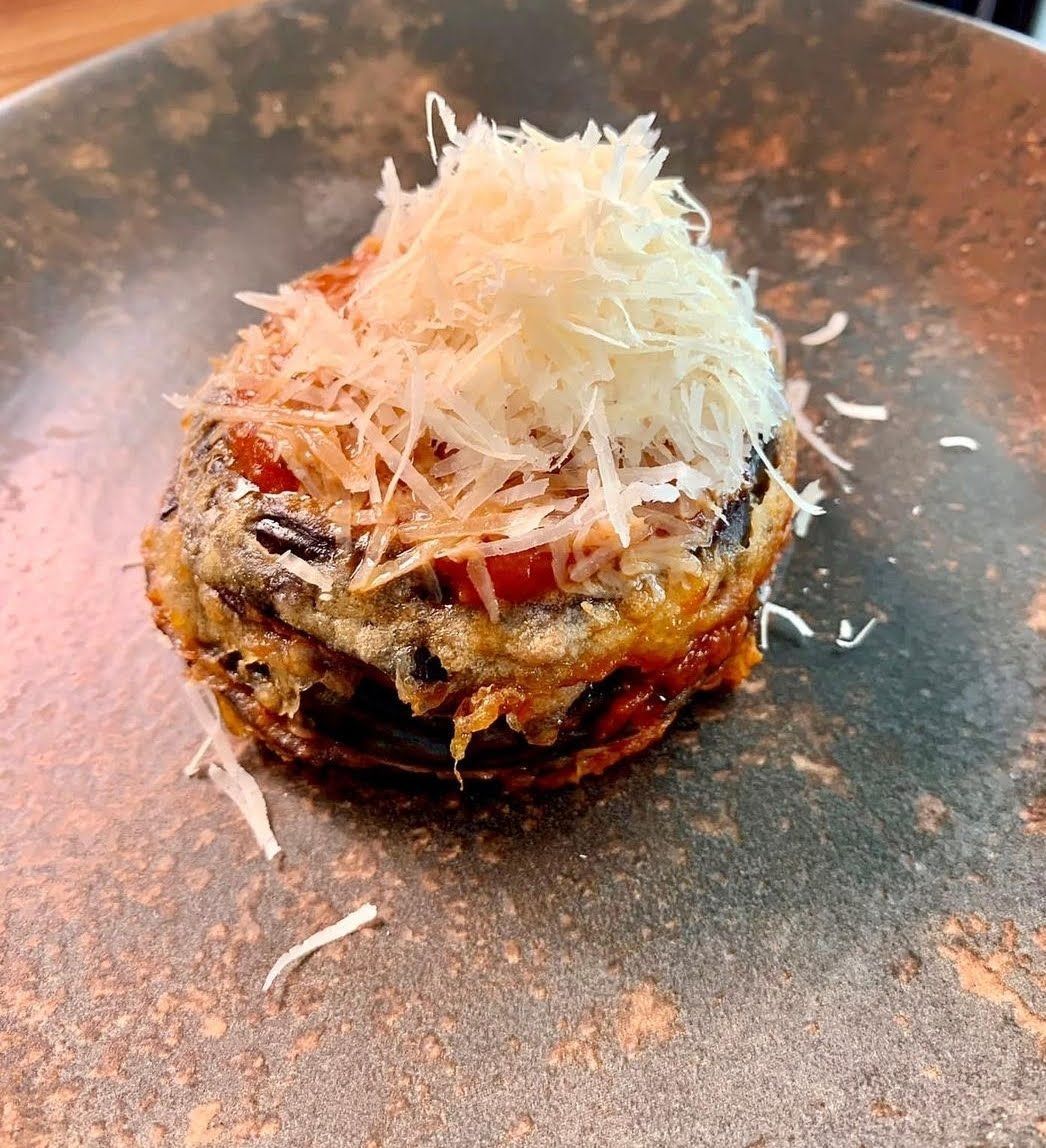 Un primer plano de un plato de comida con queso encima.