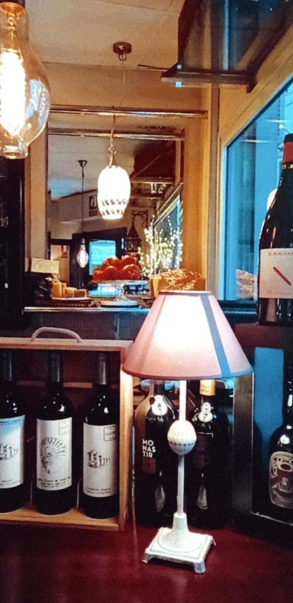 Una mesa con botellas de vino y una lámpara encima.