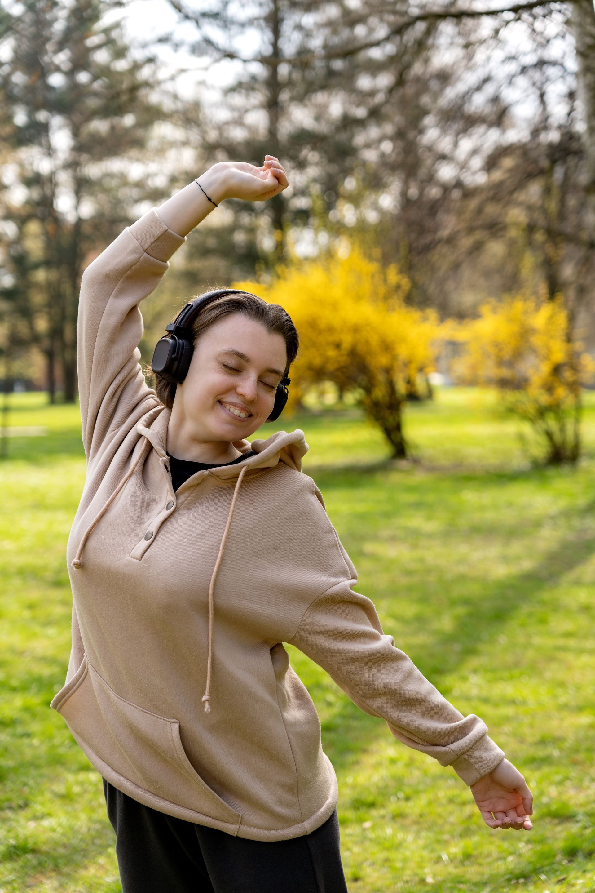 Une fille portant un casque sur les oreilles tendant les bras dans la nature