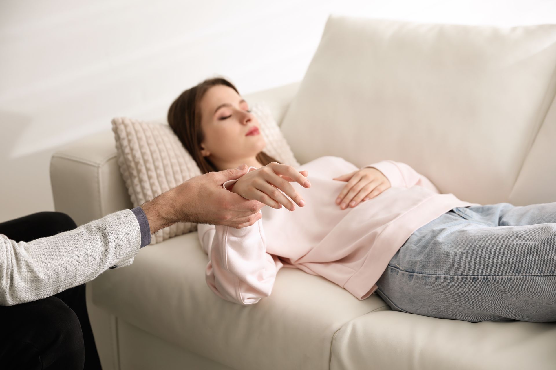 La thérapeute tient le poignet d'une dame qui est allongée sur un canapé