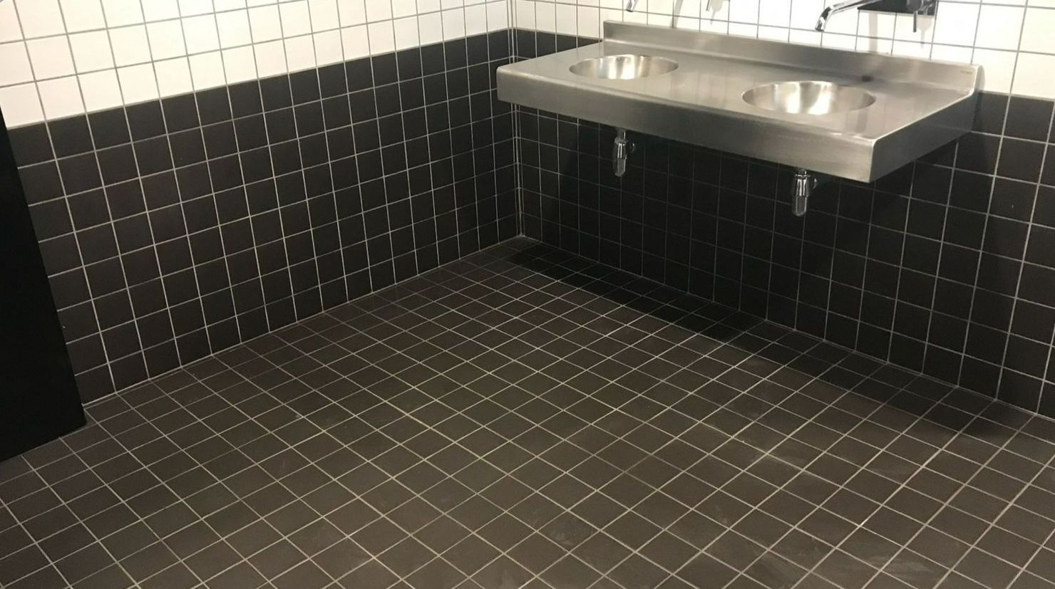Salle de bains propre à carrelage noir et blanc et évier en inox